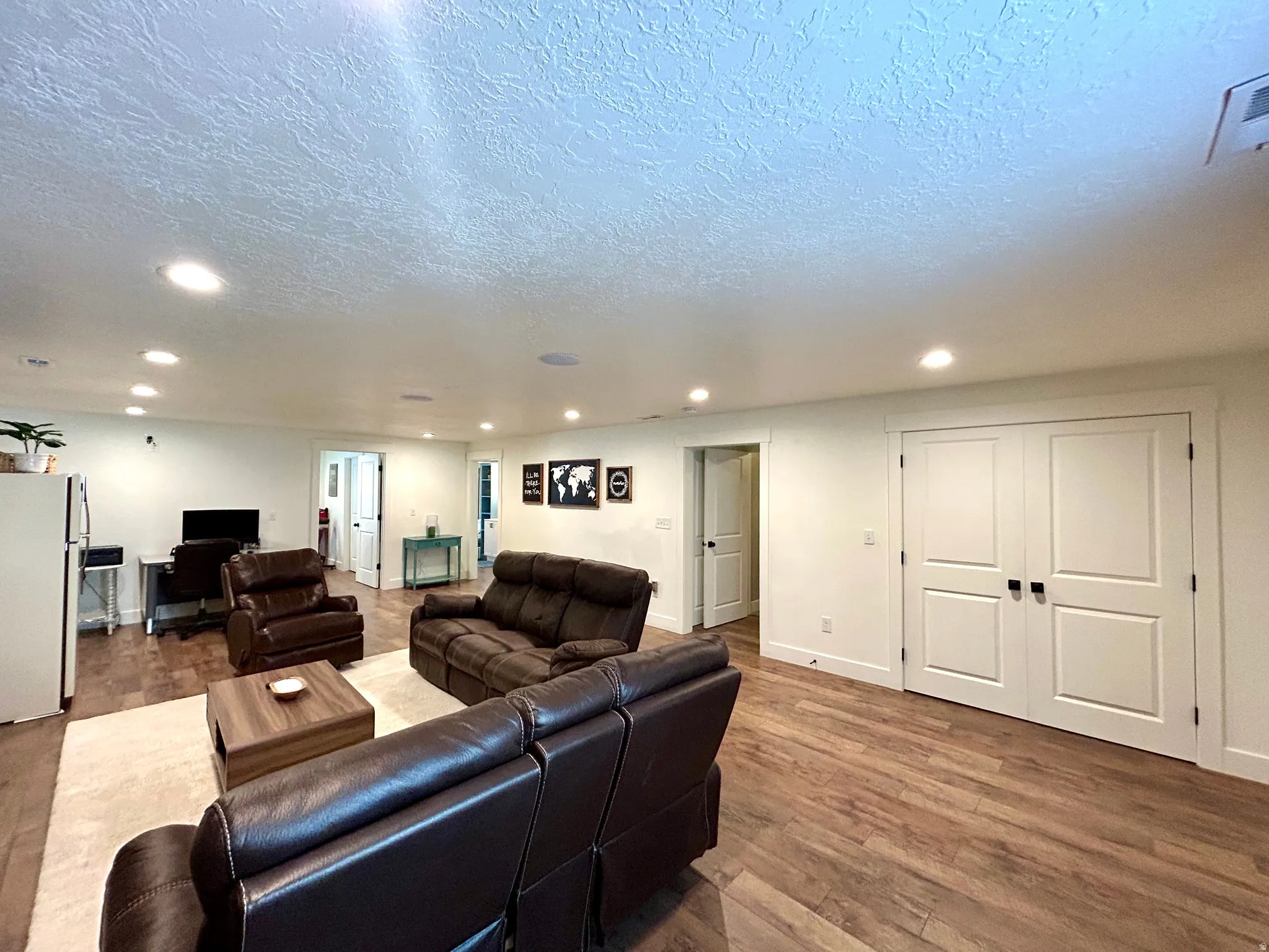 Spacious open-concept room featuring wood-finish flooring, recessed lighting, and white baseboards