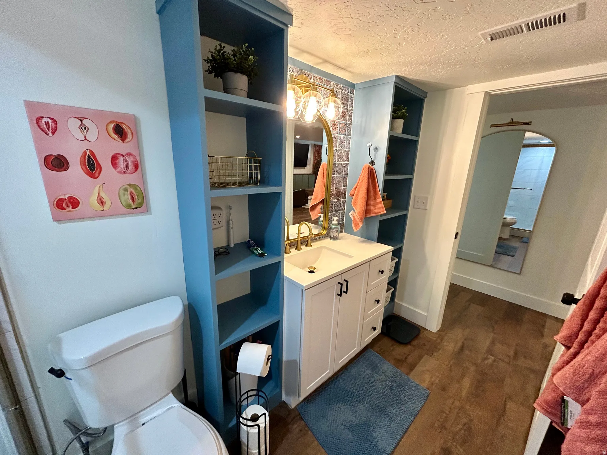 Bathroom featuring a white vanity with gold-finish fixtures, patterned wall tile, and wood-finish flooring