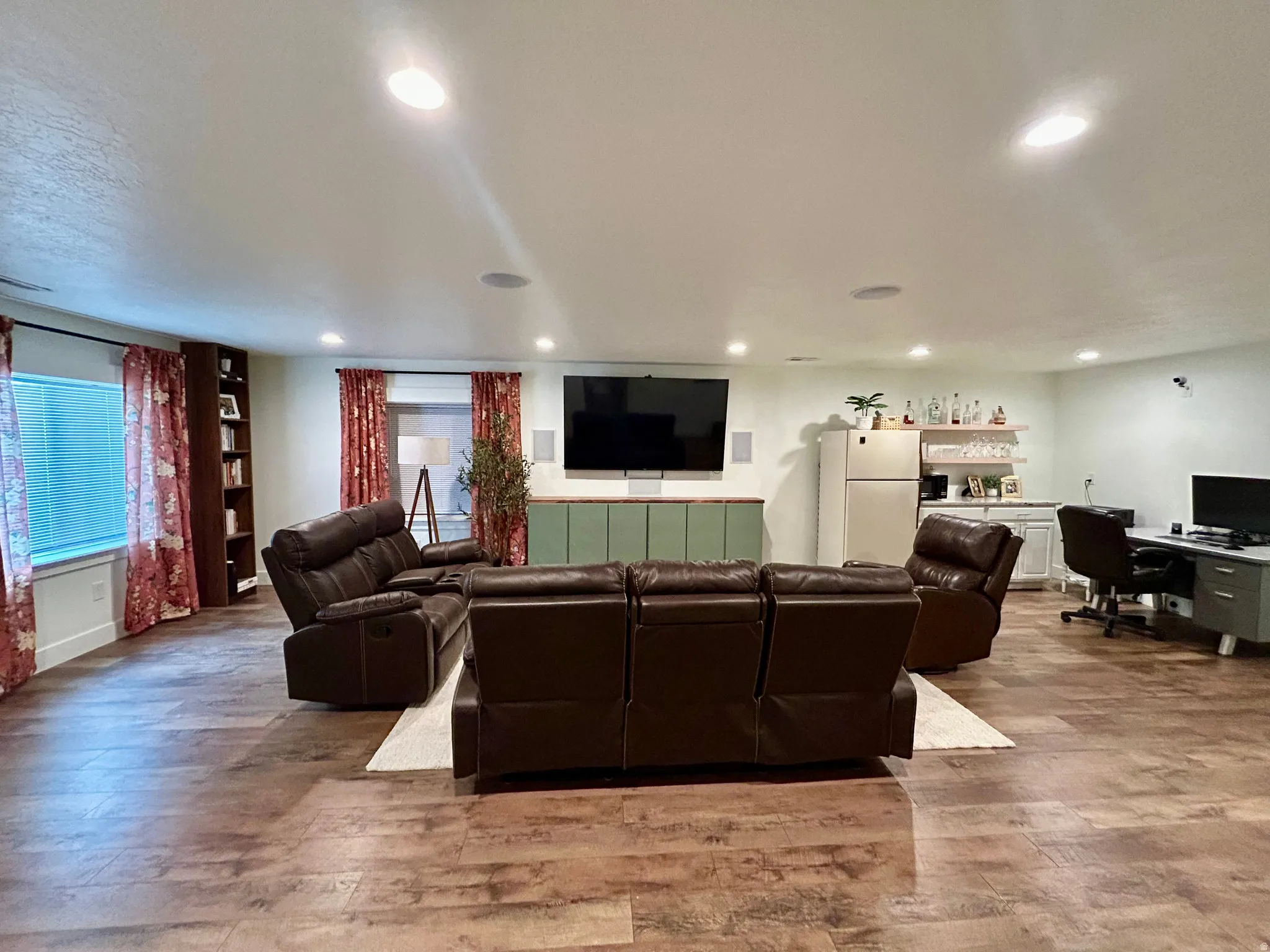 Spacious entertainment area featuring wood-finish flooring, recessed lighting, and built-in shelving