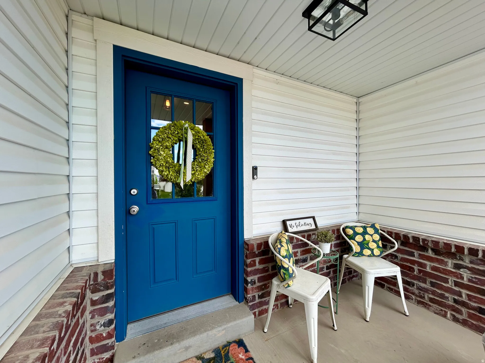 Front entry featuring a vibrant blue door with upper lites, white siding, and a red brick foundation