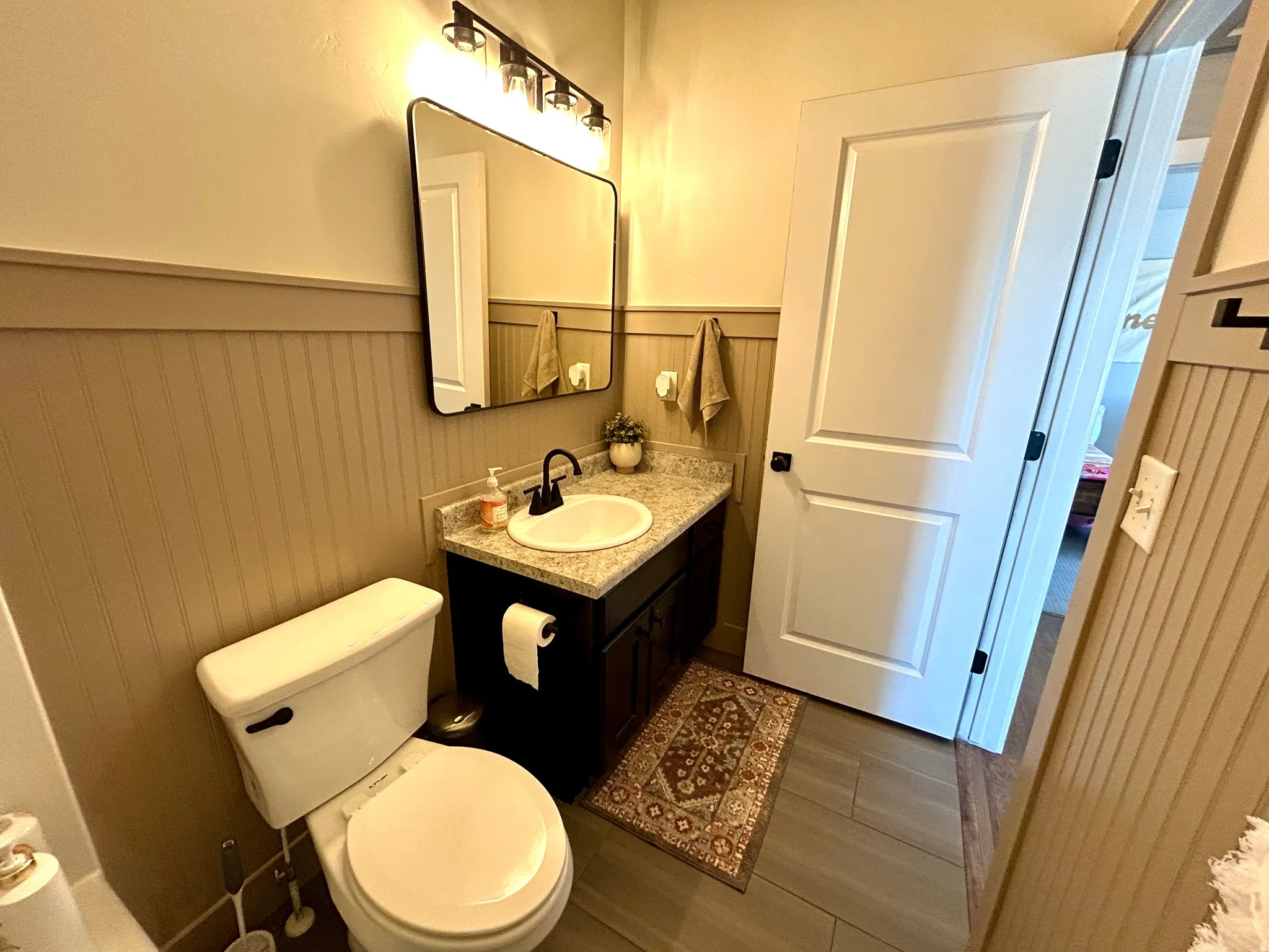 Bathroom featuring a dark wood-finish vanity with a light speckled countertop, a rectangular mirror, and a three-light fixture