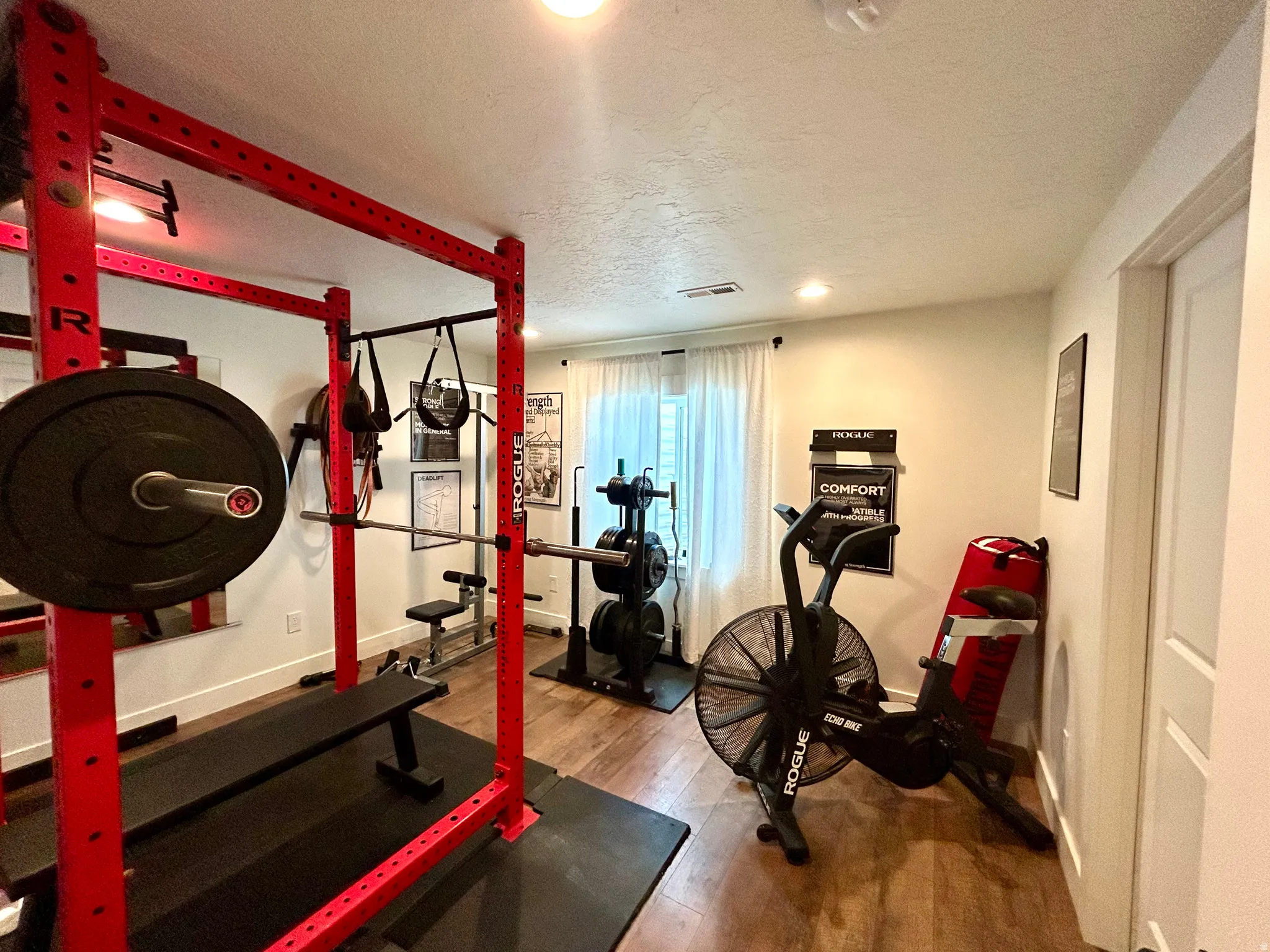 Dedicated fitness space featuring wood-finish flooring, recessed lighting, and a white paneled door