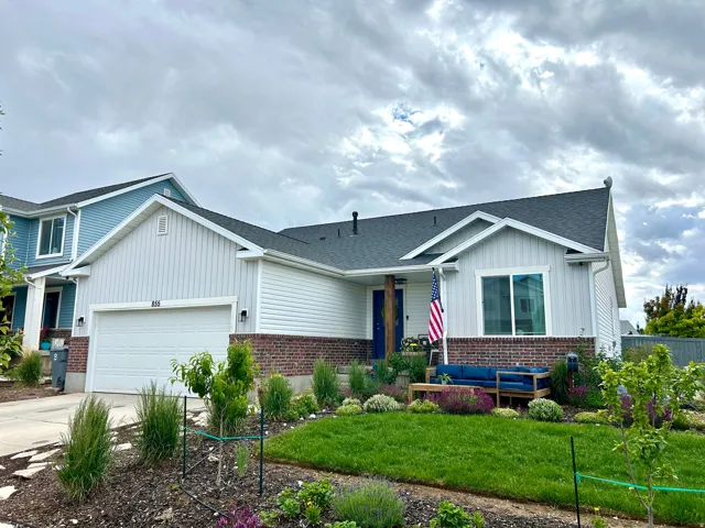 Front exterior featuring white siding with vertical accents, dark shingle roof, and a brick facade