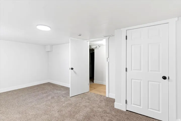 Carpeted bedroom featuring a ceiling-mounted light fixture, white walls, and white trim.