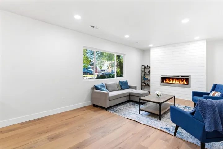 Spacious living area featuring electric fireplace, wood-finish flooring, recessed lighting, and white walls