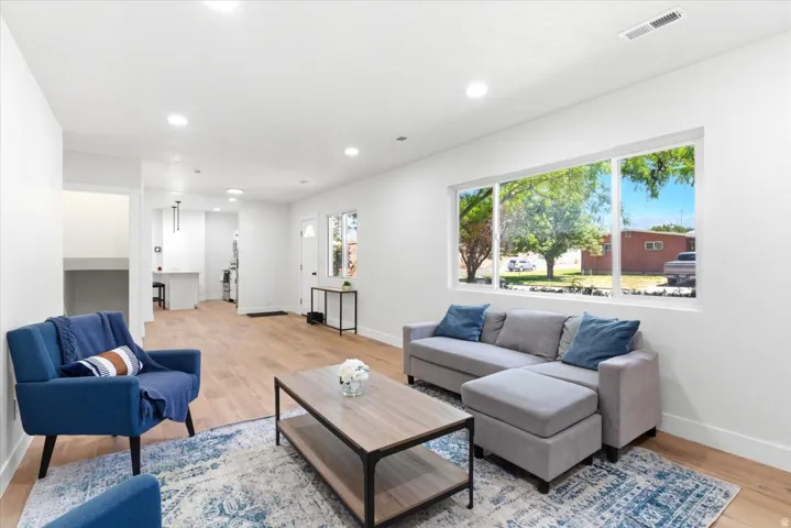 Open-concept living space featuring wood-finish flooring, recessed lighting, and a large picture window.