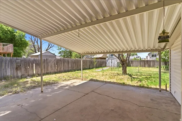 Concrete patio with a corrugated metal awning, bordered by a wooden fence