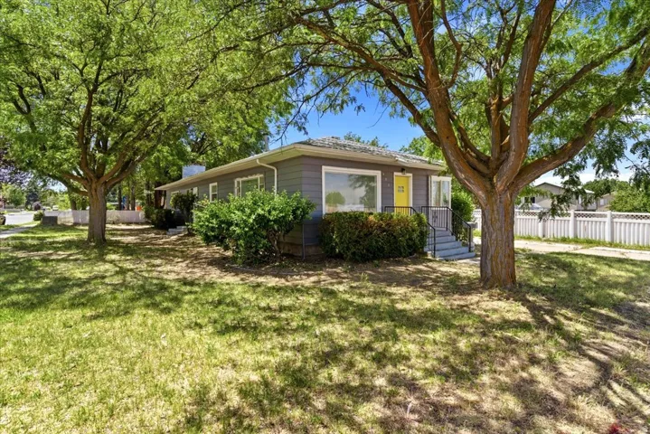 Ranch-style residence featuring a gray exterior siding, large front windows, and a vibrant yellow entry door.