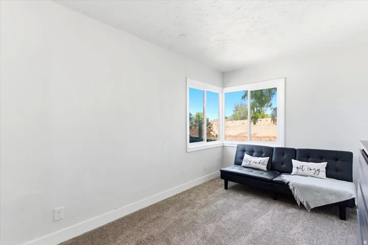 Corner window configuration with white trim, light gray walls, and textured carpet flooring