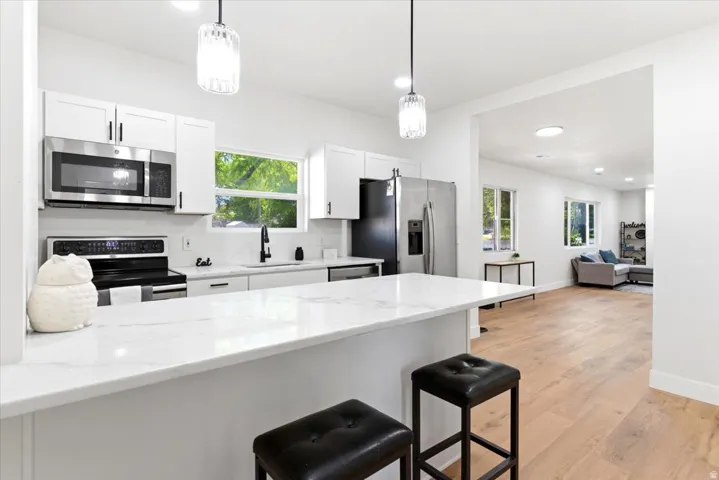Modern kitchen featuring white shaker cabinetry, stainless steel appliances, and a substantial breakfast bar with a quartz-finish countertop.