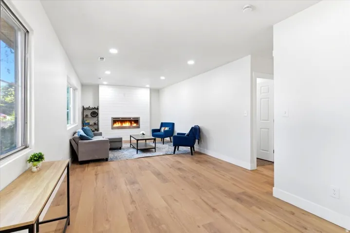 Spacious living area featuring electric fireplace, wood-finish flooring, recessed lighting, and white walls
