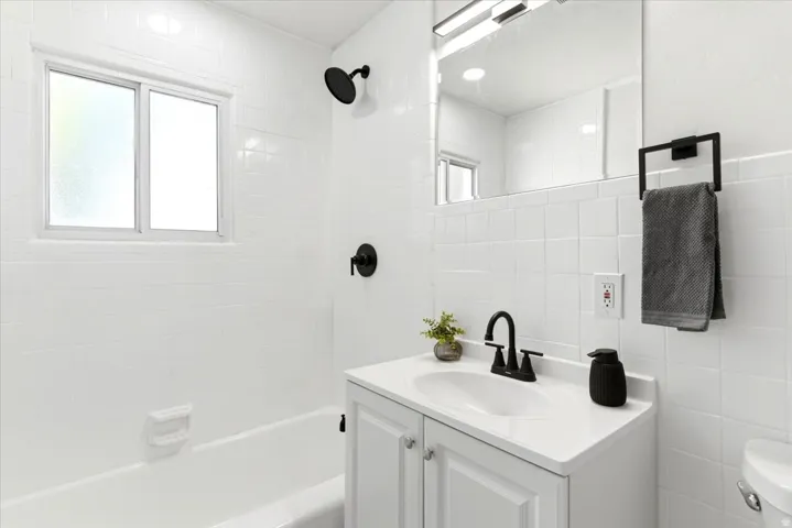 Modern bathroom featuring a white vanity with an integrated sink and matte black faucet, surrounded by white subway tile