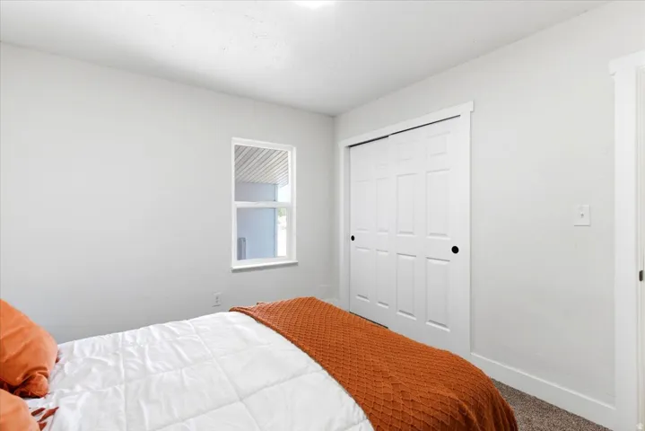 Neutral interior walls with a window, white trim, and a bi-fold closet door featuring black hardware