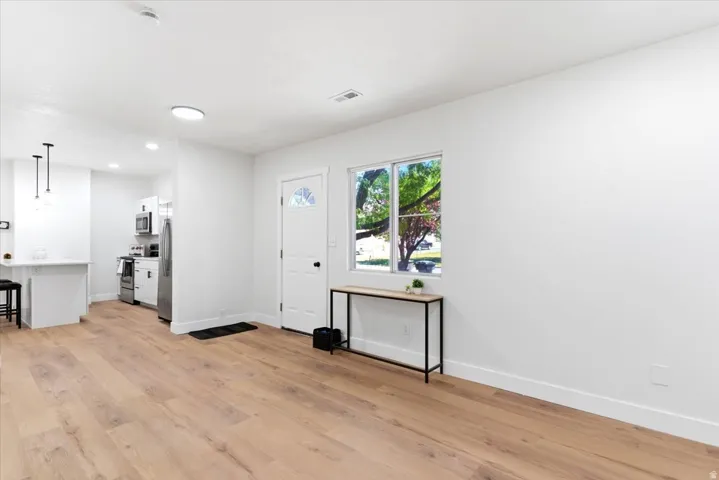 Open-concept living area featuring wood-finish flooring, white walls, and recessed lighting