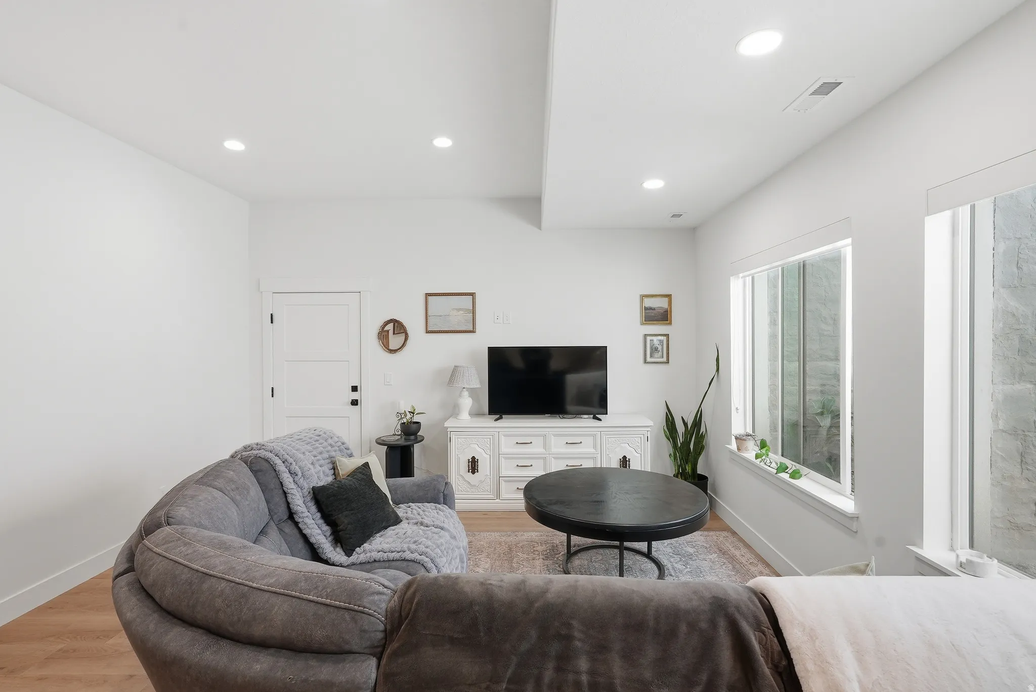 Living area featuring recessed lighting, light LVP flooring, white walls, and multiple windows