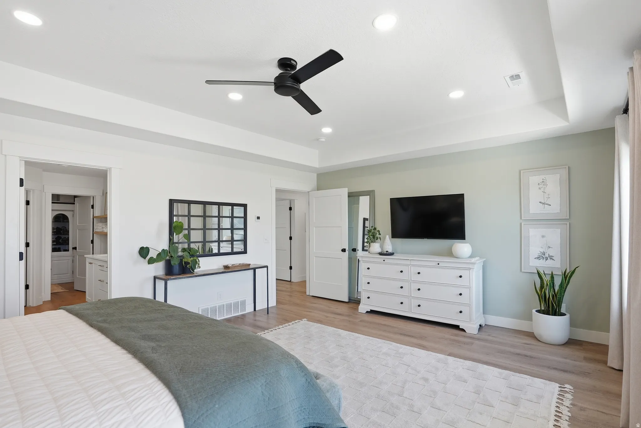Spacious room featuring light LVP flooring, a tray ceiling with recessed lighting and a ceiling fan, and a neutral color palette