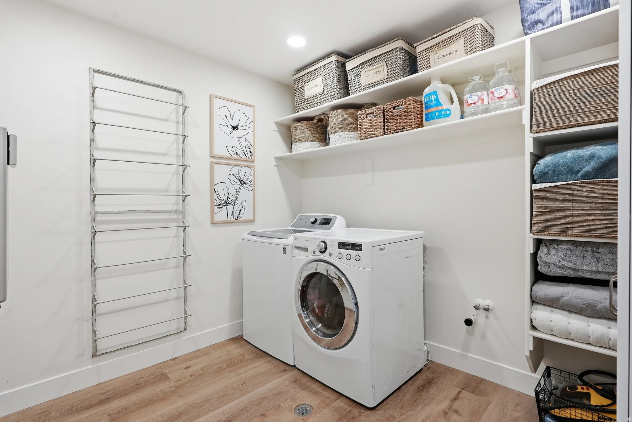 Dedicated laundry area featuring wood-finish flooring, white walls, and bright overhead lighting