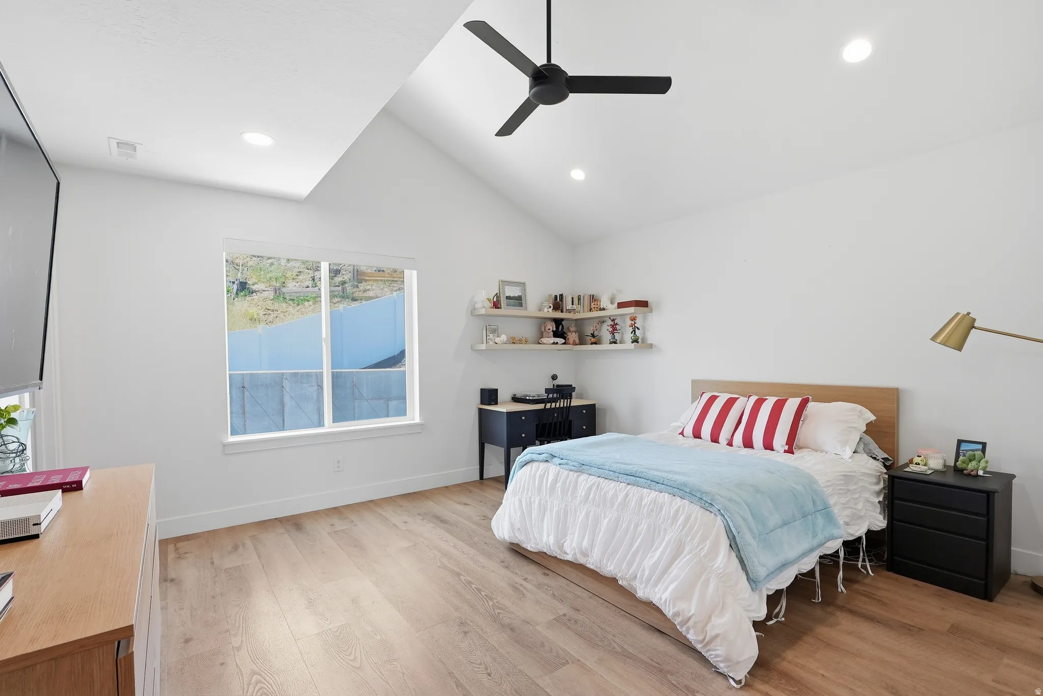 Spacious room featuring vaulted ceilings, LVP flooring, a large window, a ceiling fan, and recessed lighting