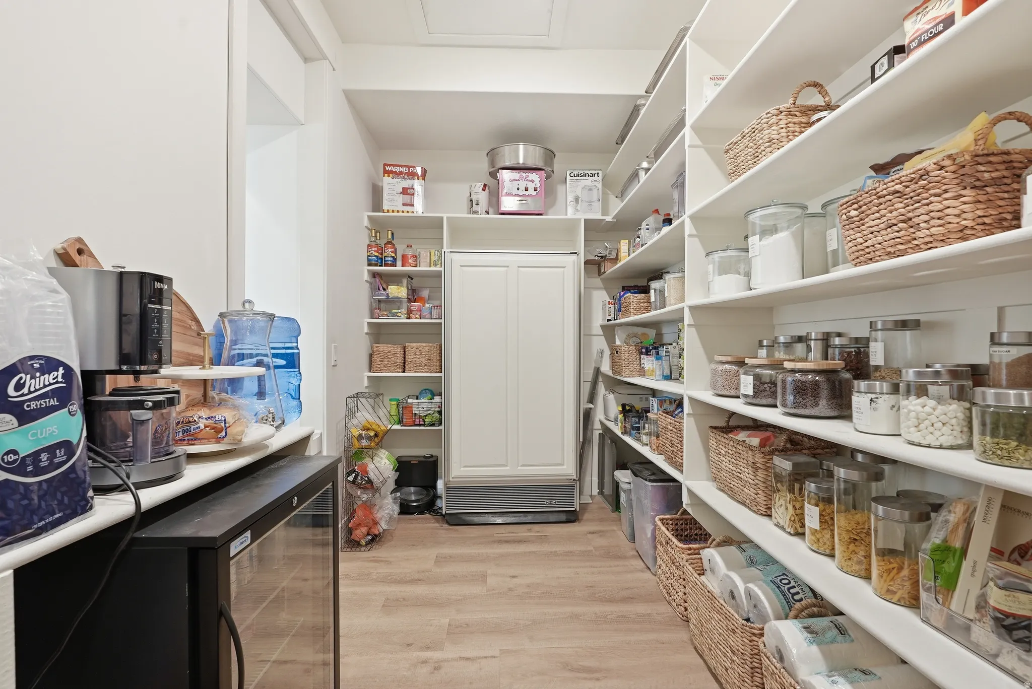 Spacious pantry with extensive built-in shelving, LVP flooring, a beverage cooler, and a built-in upright freezer