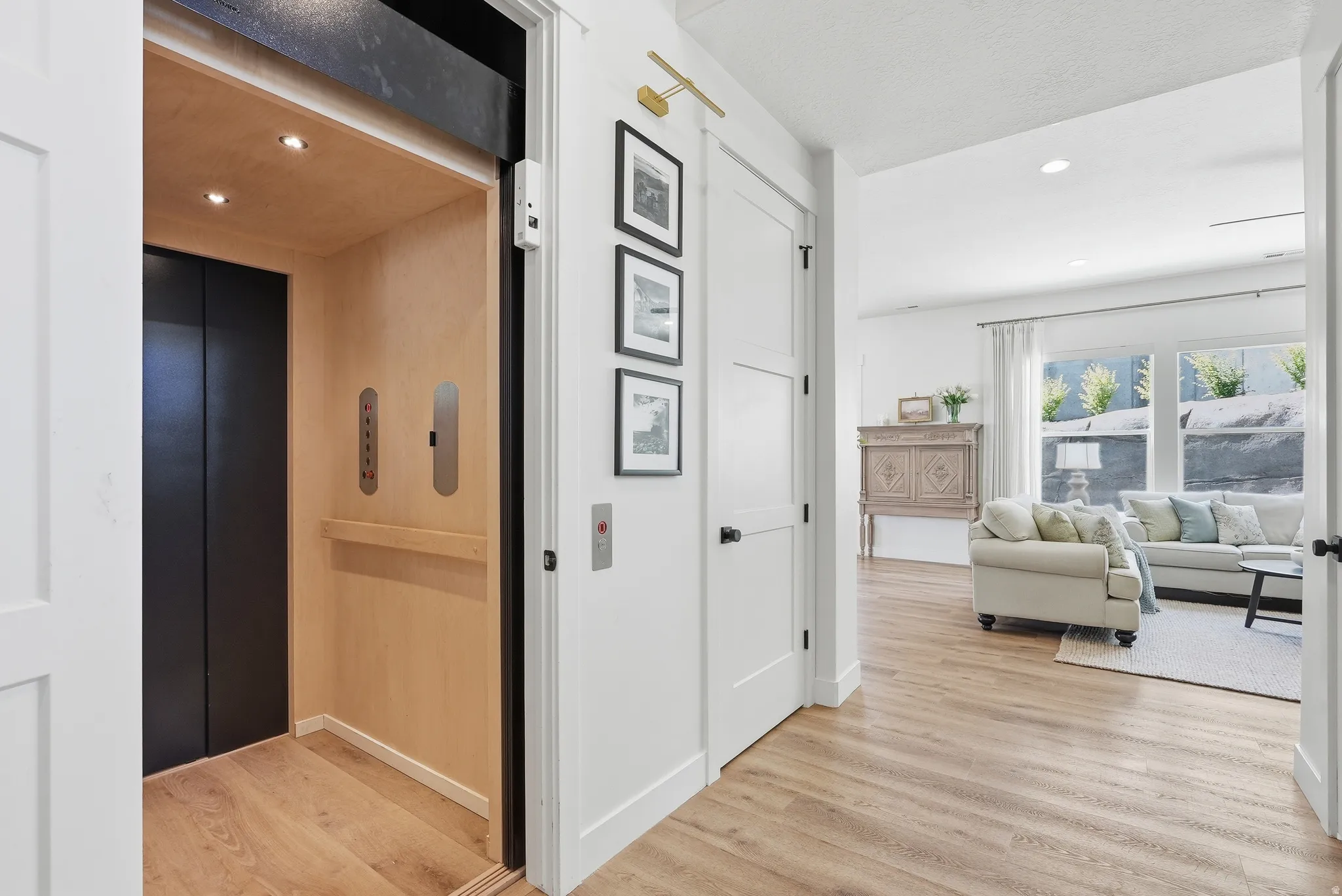 In-home elevator featuring wood-finish paneling, recessed lighting, and black sliding doors