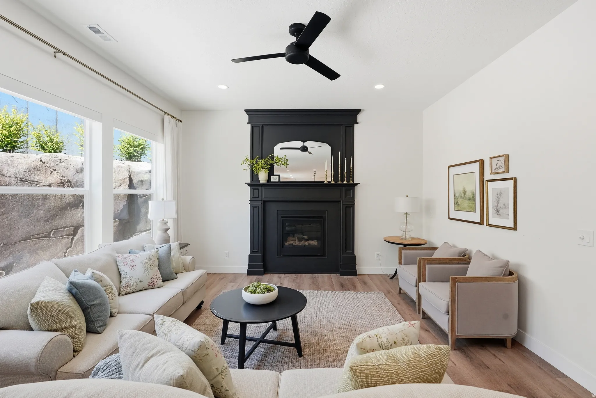Living area featuring a black fireplace with a detailed mantel, wood-finish flooring, recessed lighting, and a modern ceiling fan