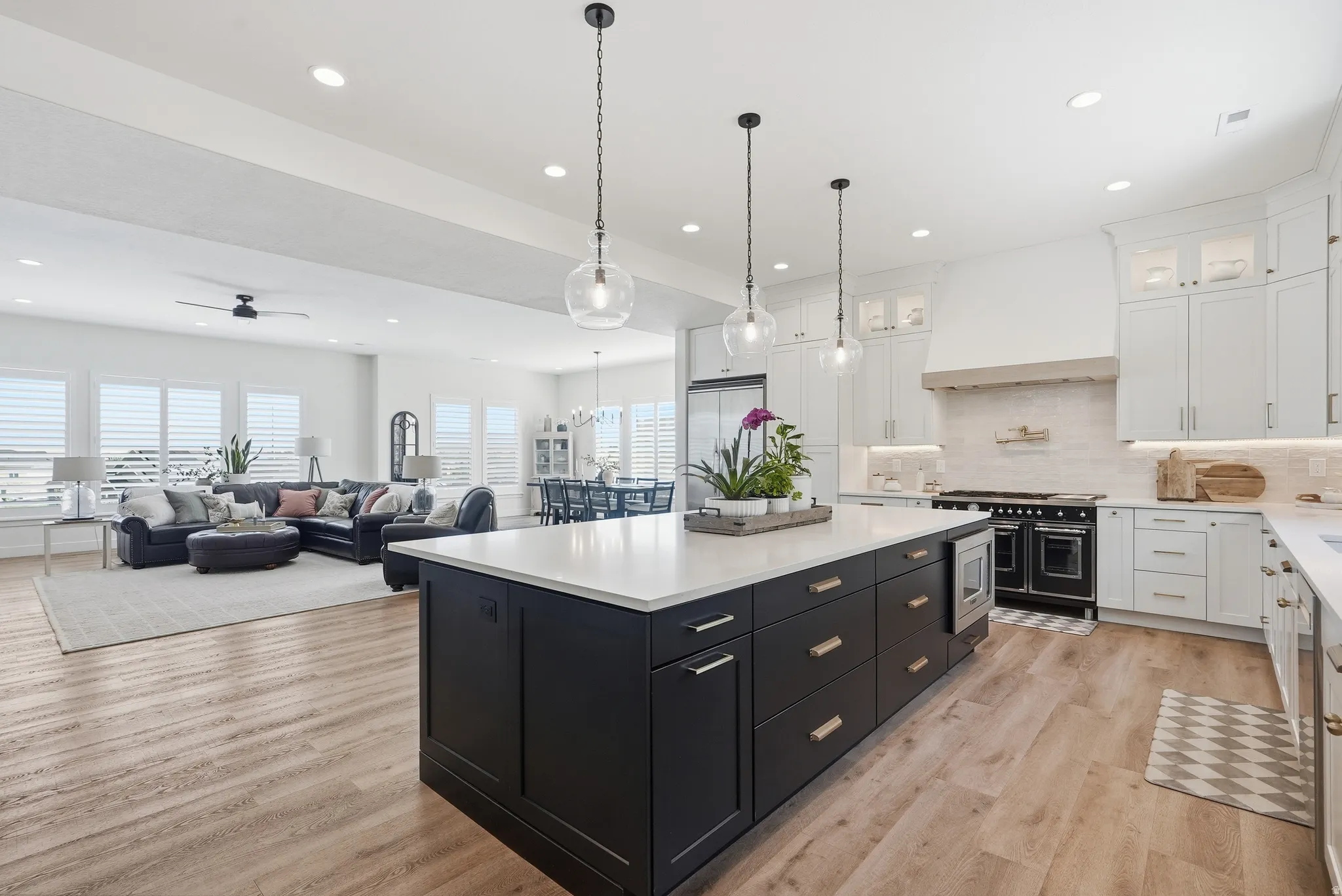 Spacious open-concept living area featuring a large kitchen island with integrated microwave, LVP flooring, recessed lighting, and white cabinetry