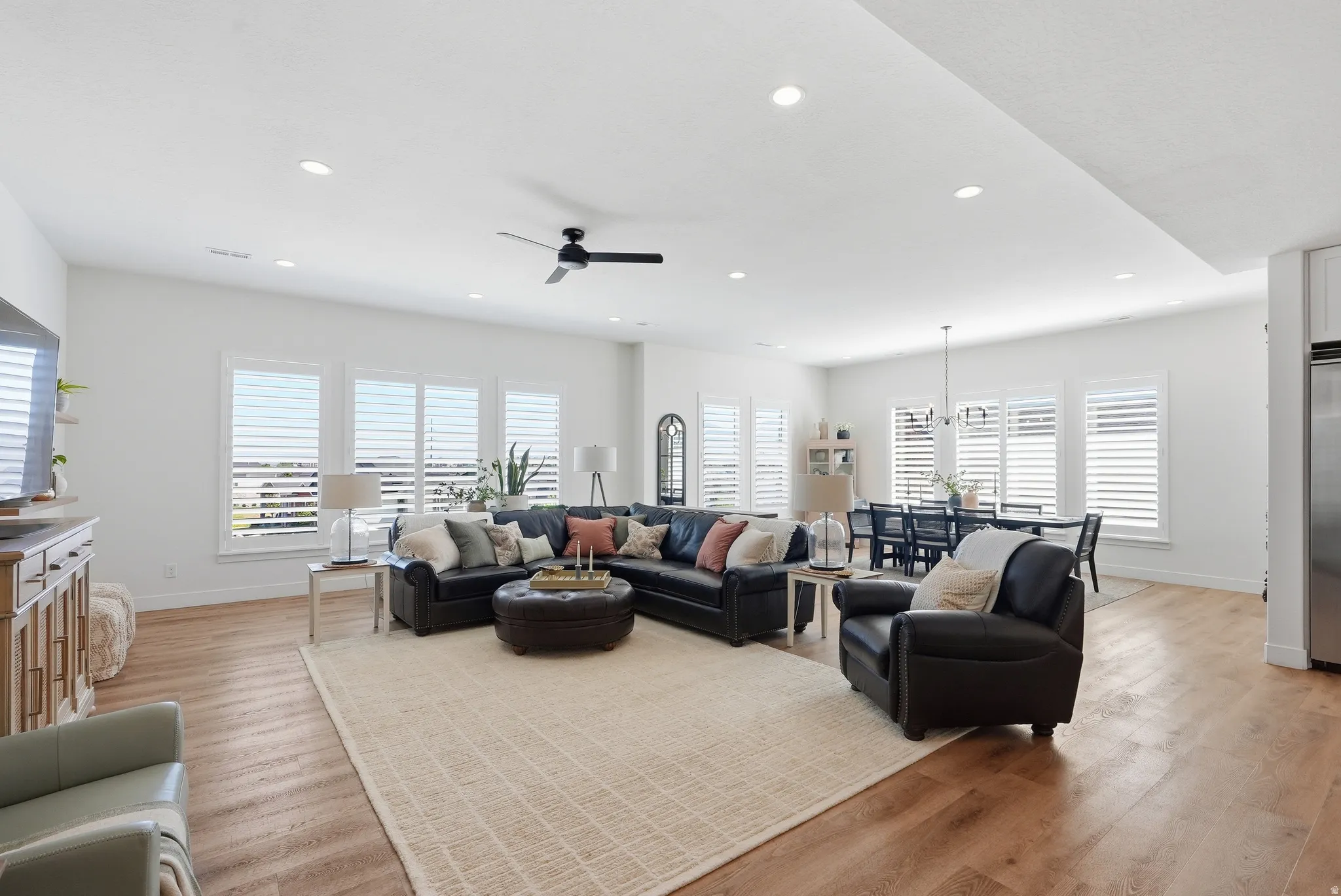 Open-concept living area featuring LVP flooring, recessed lighting, and multiple windows with plantation shutters