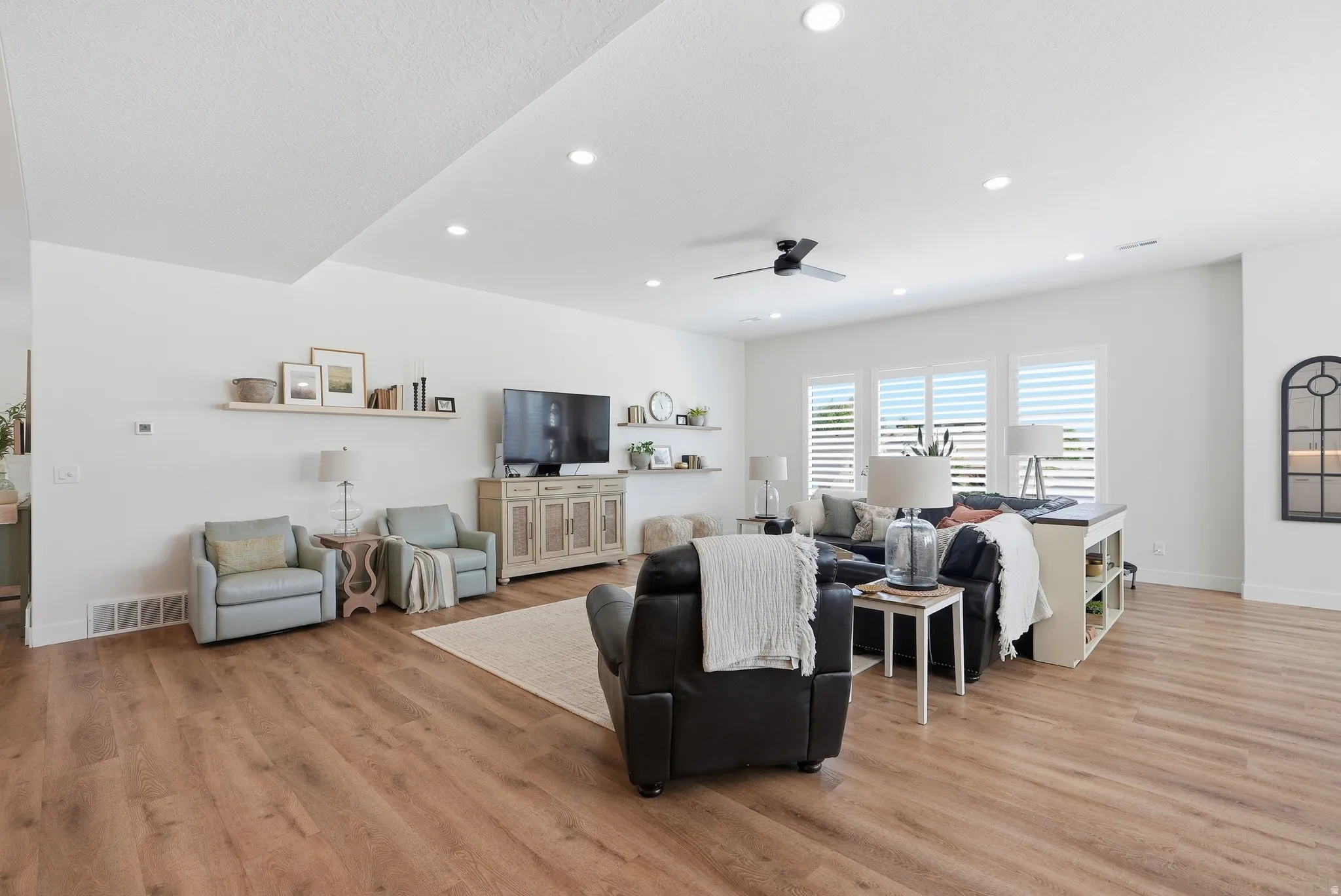 Spacious living area featuring LVP flooring, recessed lighting, and a ceiling fan