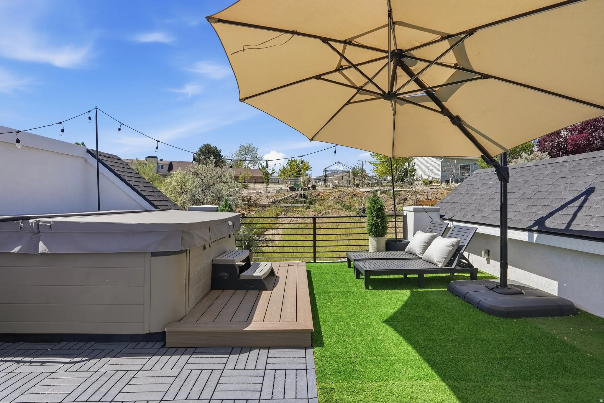 Rooftop deck featuring a built-in hot tub, artificial turf, string lighting, and a metal railing