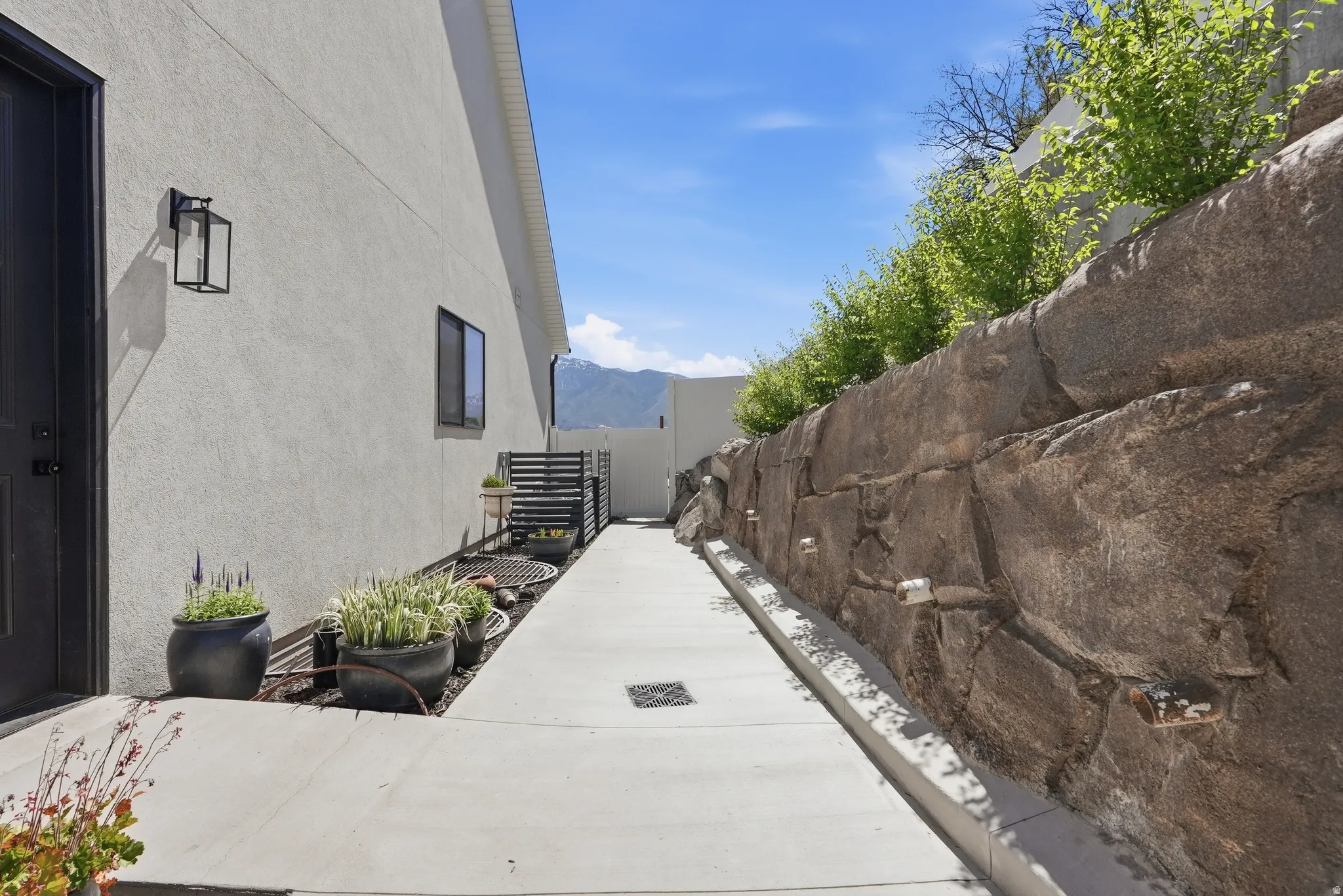 Concrete walkway bordered by a large natural stone retaining wall with integrated lighting