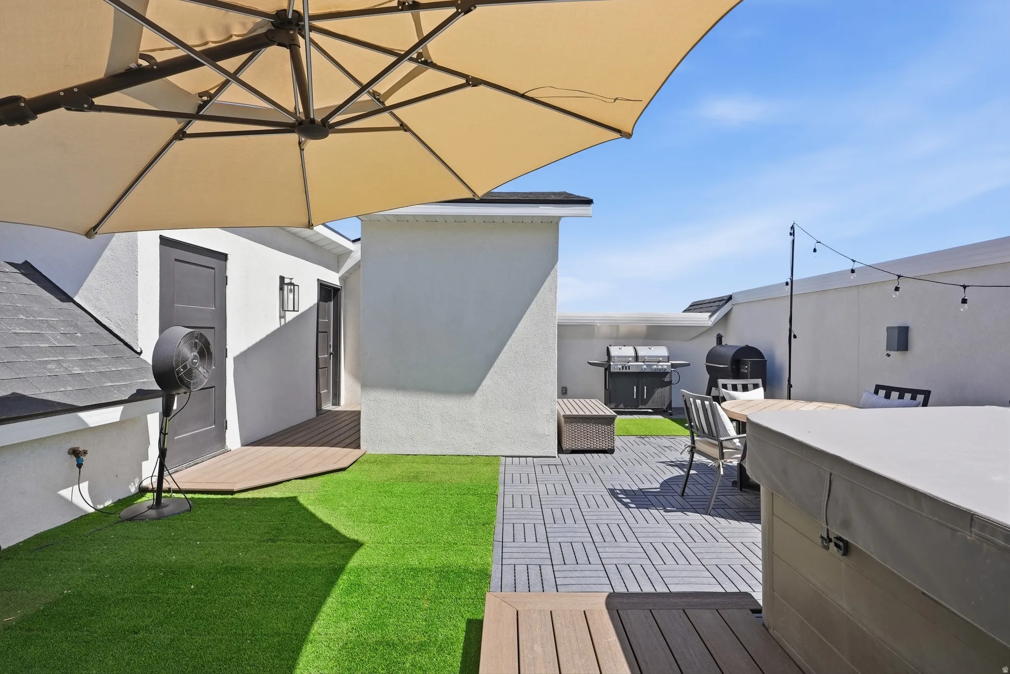 Rooftop patio featuring artificial turf, modular tile flooring, and string lighting