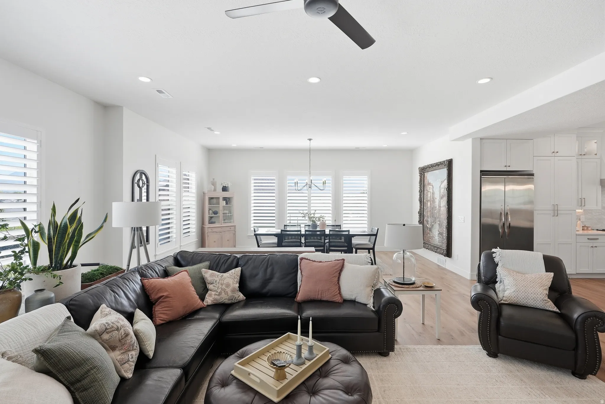 Spacious living area featuring light LVP flooring, recessed lighting, and a modern ceiling fan