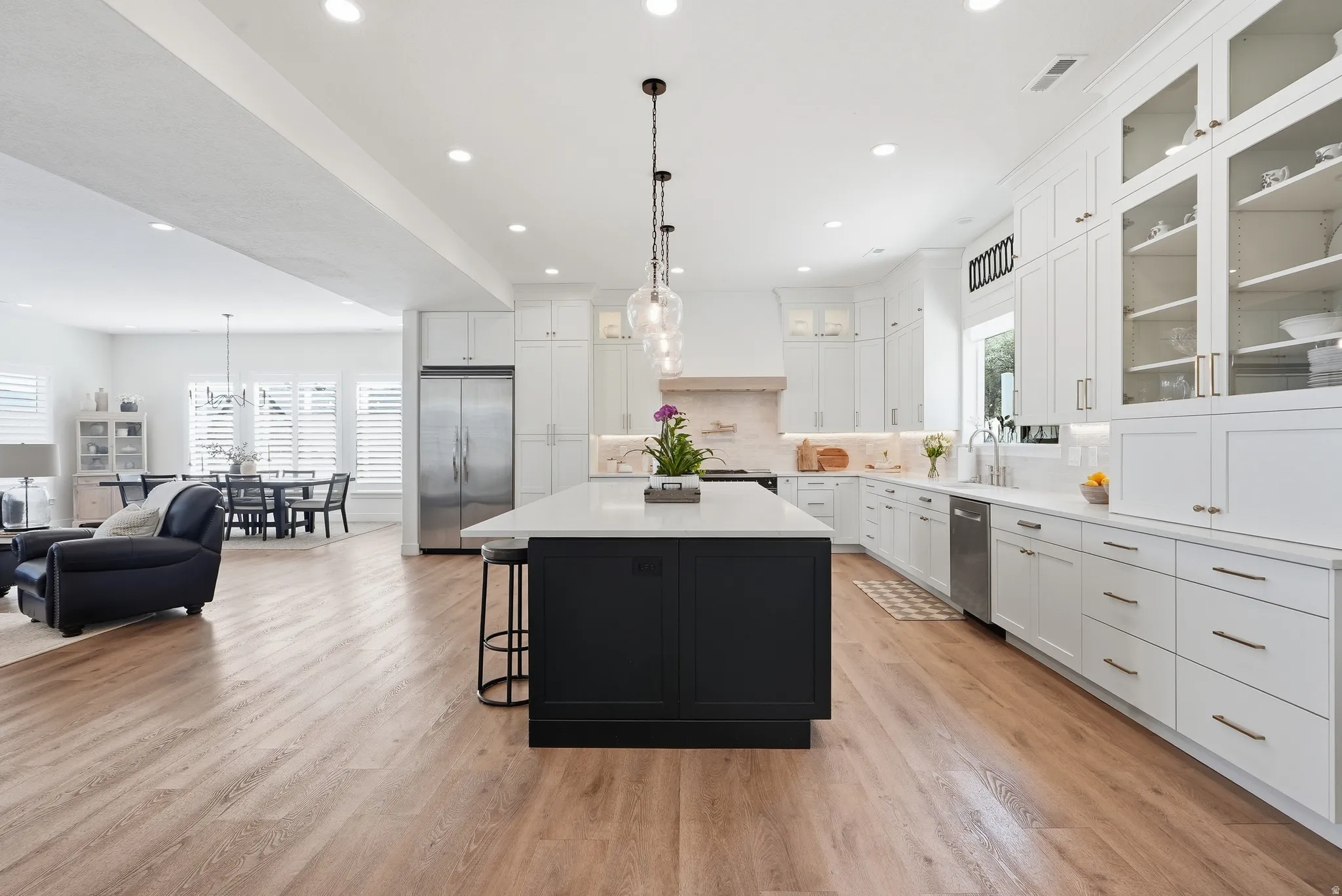 Spacious kitchen featuring a large central island with seating, white shaker cabinetry, stainless steel appliances, and LVP flooring