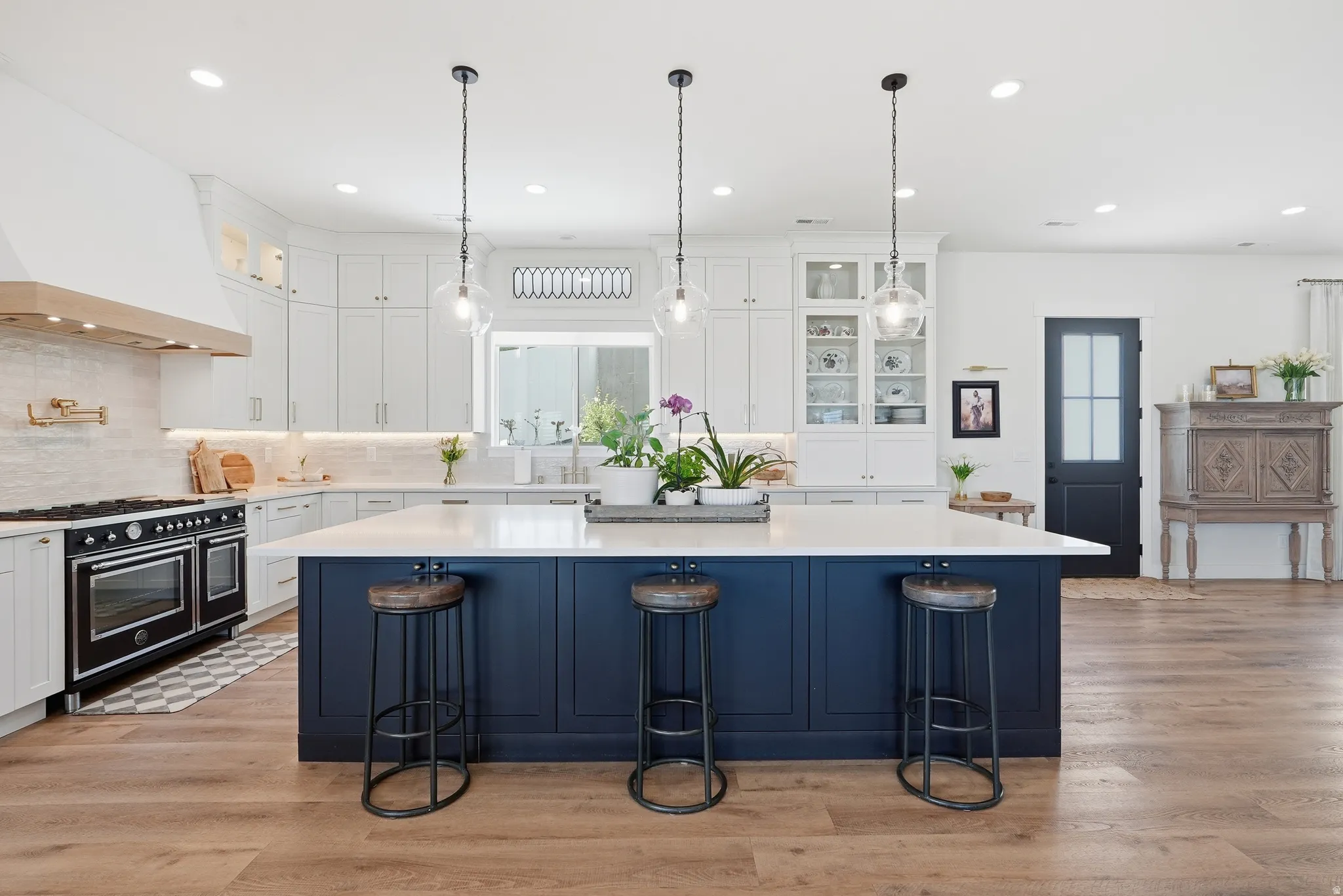 Spacious kitchen featuring a large blue island with white countertop, integrated seating, and three pendant lights