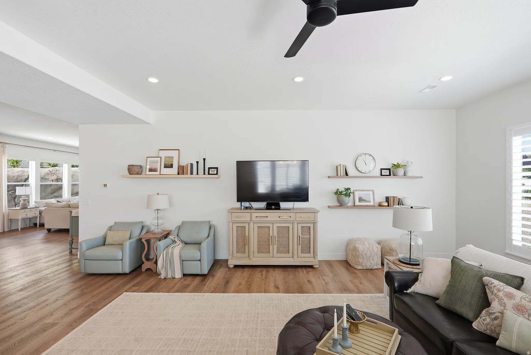 Spacious living area featuring LVP flooring, recessed lighting, and a modern ceiling fan