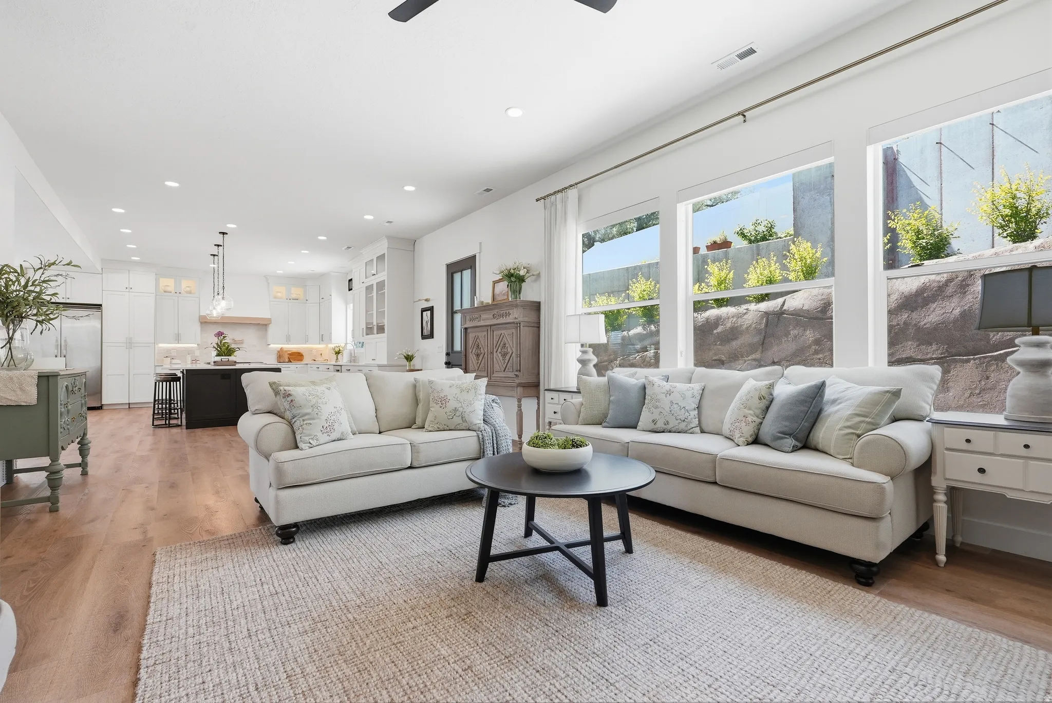 Bright, open-concept living area featuring LVP flooring, recessed lighting, and large windows