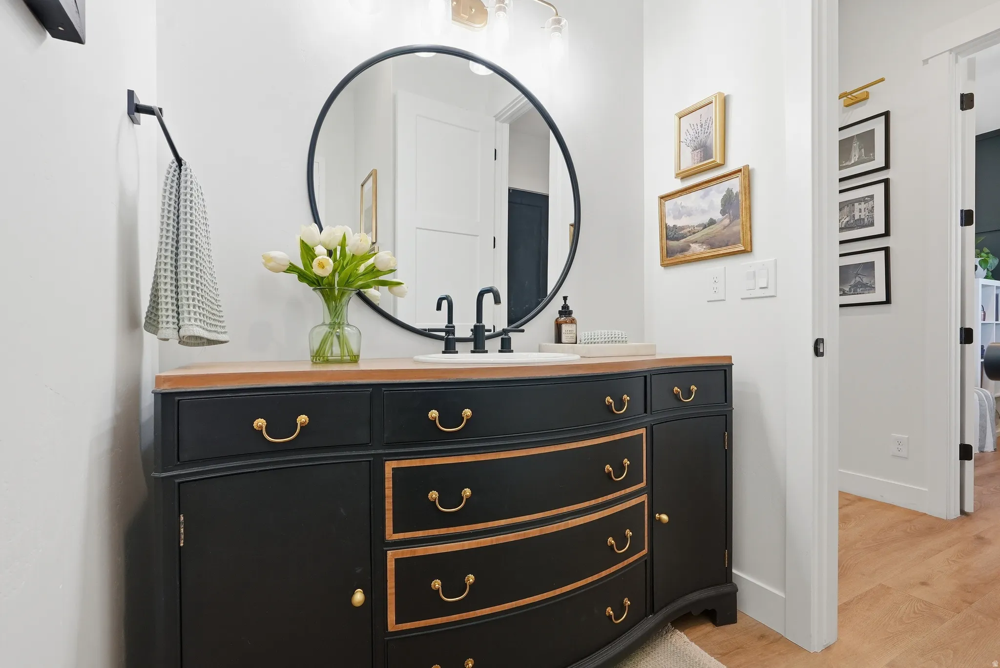 Black vanity with a wood-finish countertop and integrated basin sink