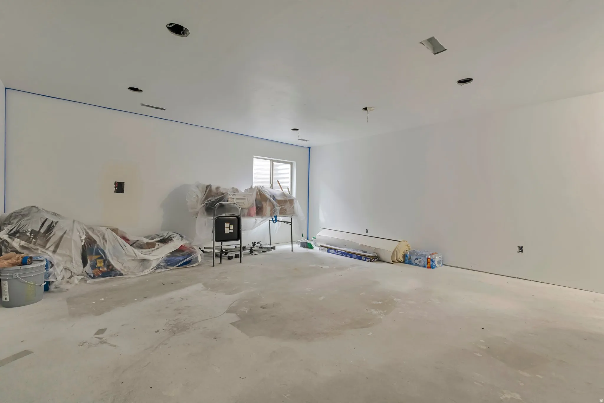 Spacious room featuring white painted walls, a concrete floor, recessed lighting, and a single window