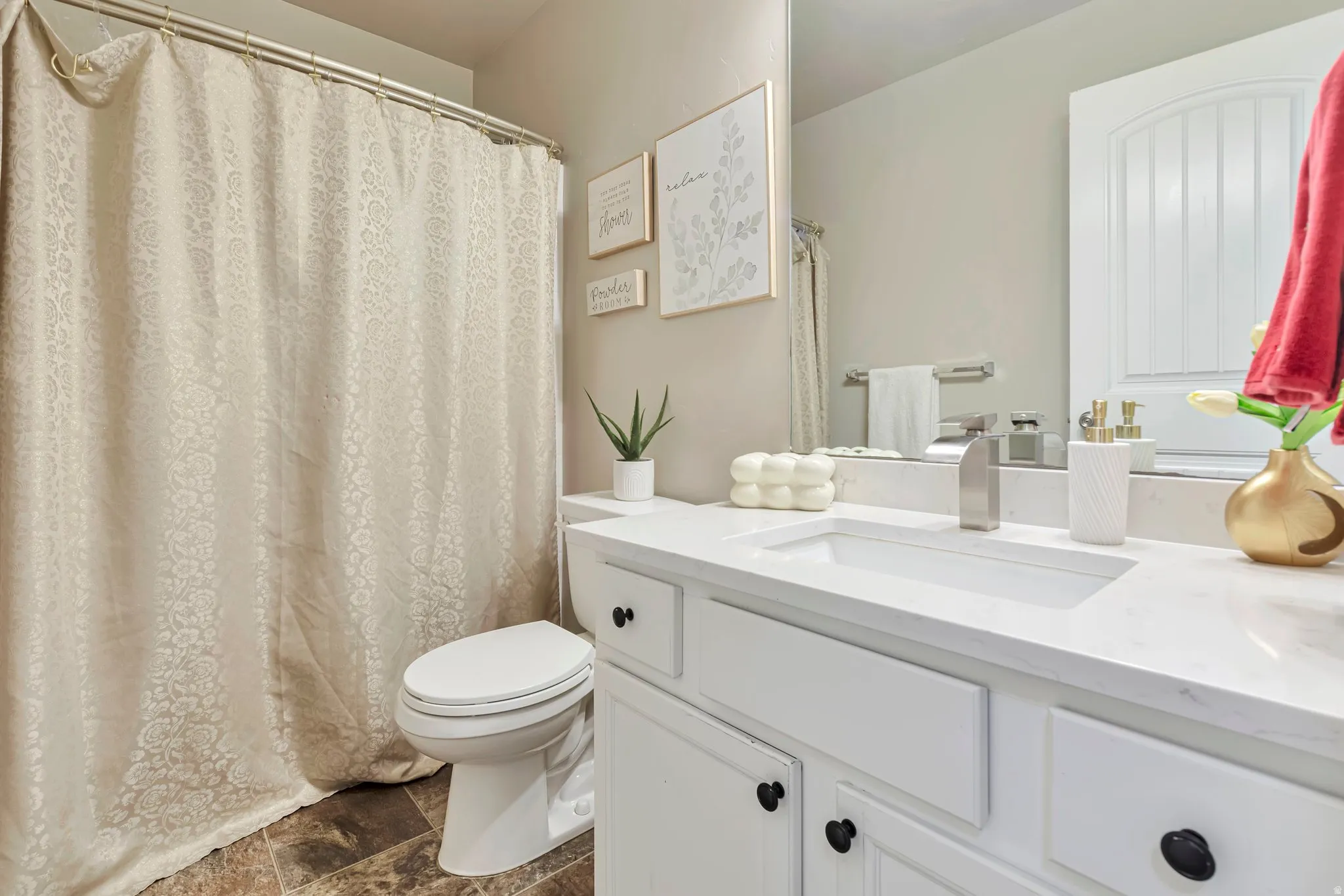 Bathroom featuring a white vanity with black hardware, an integrated sink, and a stone-finish countertop