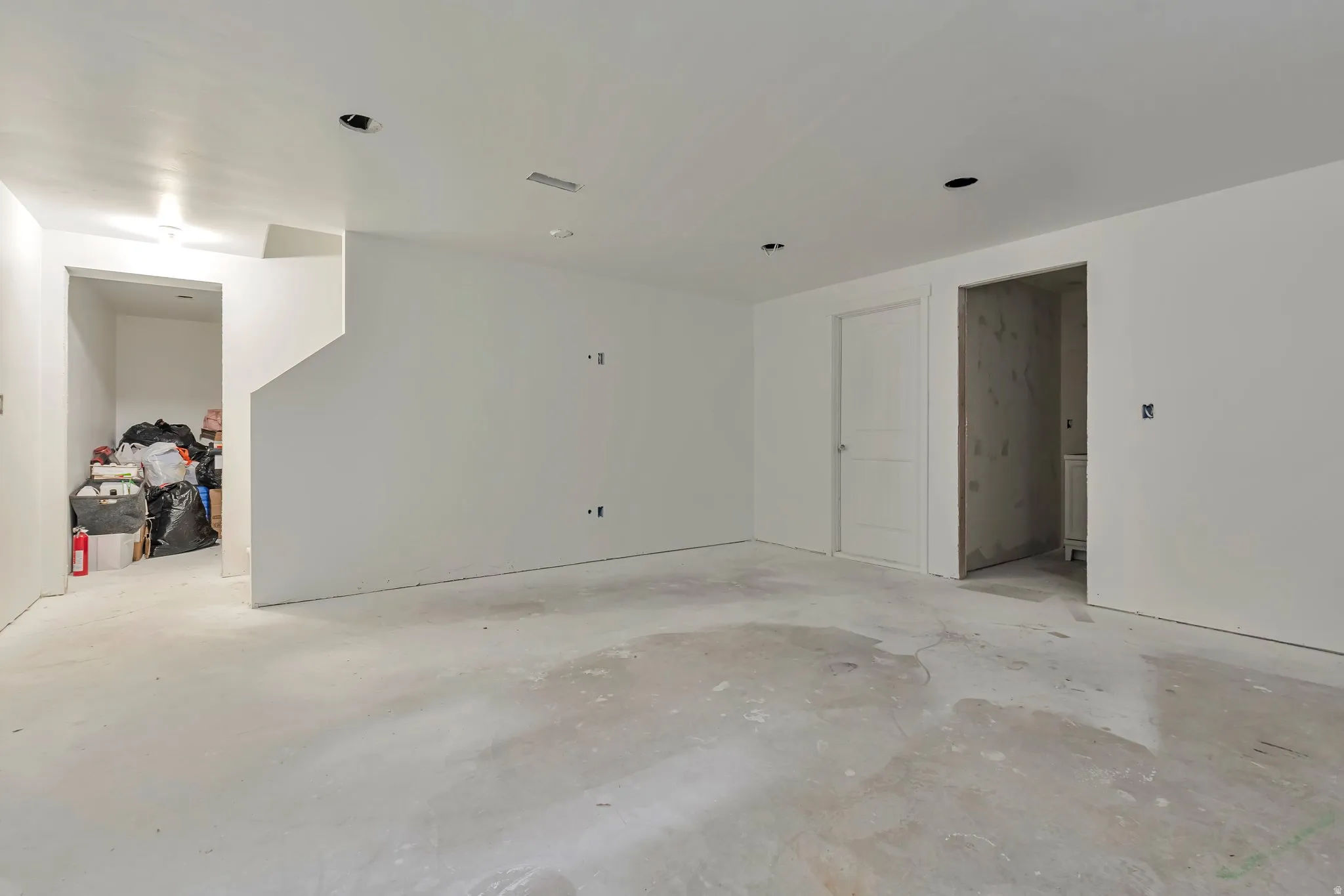 Spacious unfinished interior room featuring concrete flooring, white painted walls, and recessed lighting