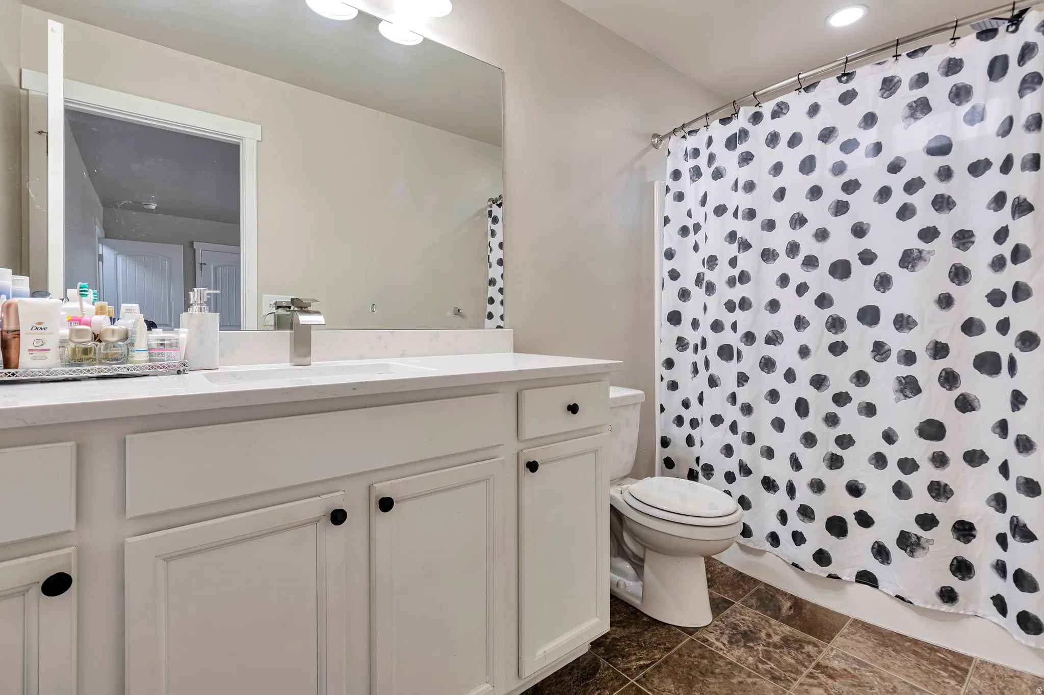 Bathroom featuring a white vanity with integrated sink, a large wall-mounted mirror, brushed nickel faucet, and recessed lighting
