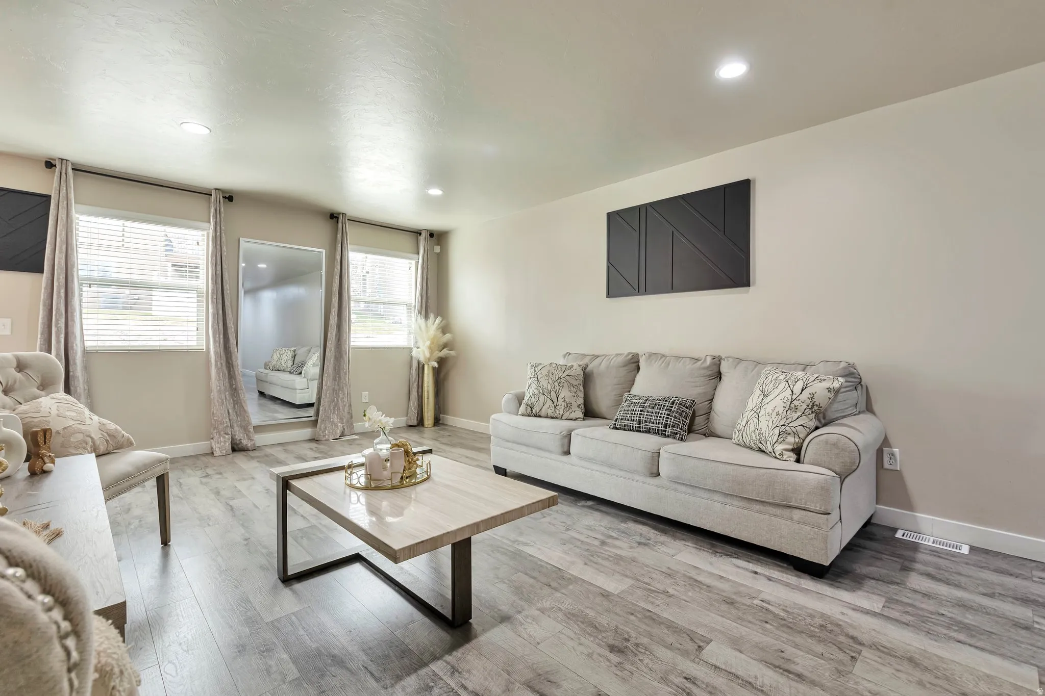 Spacious living area featuring light wood-finish flooring, neutral wall tones, and recessed lighting