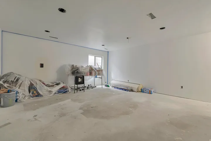 Spacious room featuring white painted walls, a concrete floor, recessed lighting, and a single window