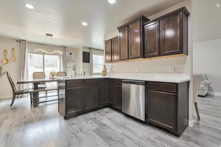 Kitchen featuring dark wood cabinetry, light-toned countertops, and a stainless steel dishwasher