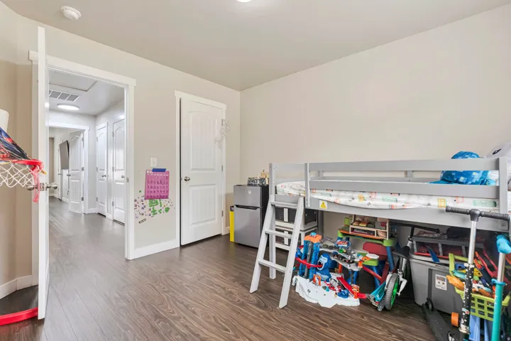 Spacious room featuring wood-finish flooring, light-toned walls, and white trim