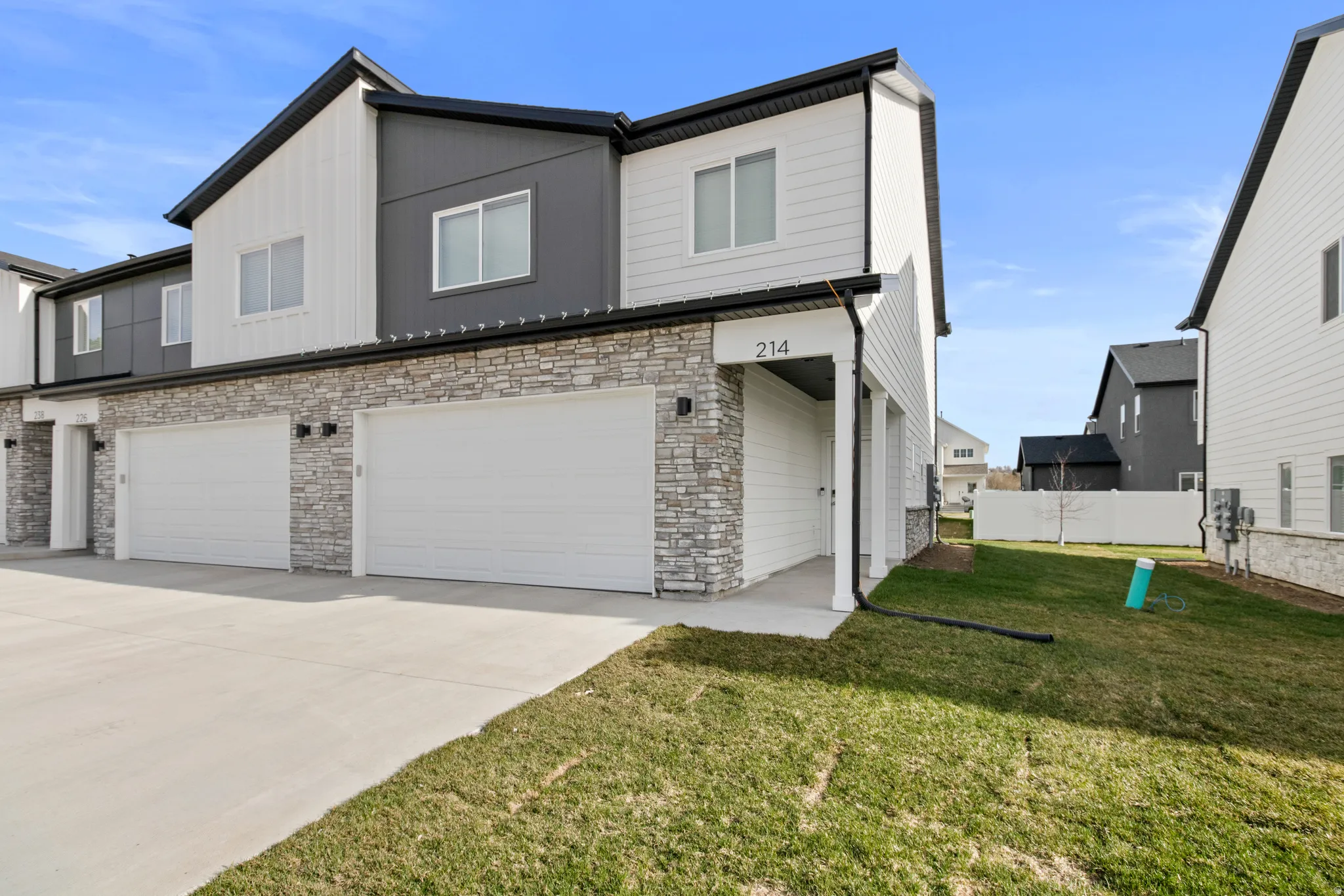 Modern two-story townhome with a grey and white exterior, featuring a stacked stone facade
