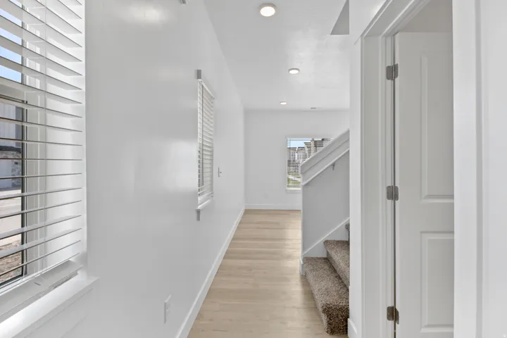 Light wood-finish flooring extending through a brightly lit hallway