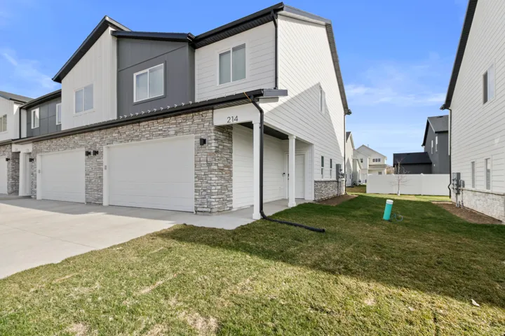 Contemporary townhome exterior featuring light siding and stacked stone accents