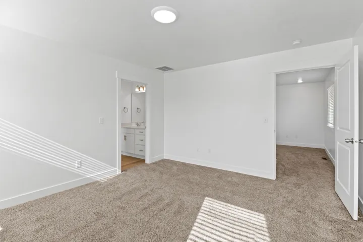 Spacious room with plush carpet flooring, recessed ceiling light, and white baseboards