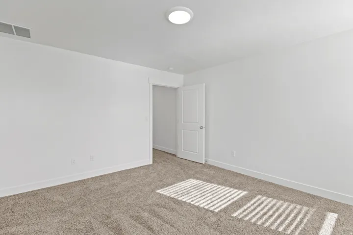 Neutral-toned wall-to-wall carpeting complements the bright white walls and trim